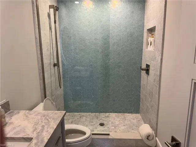 Bathroom featuring vanity, toilet, and tiled shower