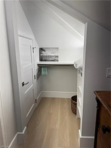 Spacious closet with light hardwood / wood-style floors and lofted ceiling