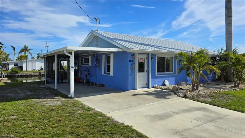 View of front facade featuring a front yard and a carport