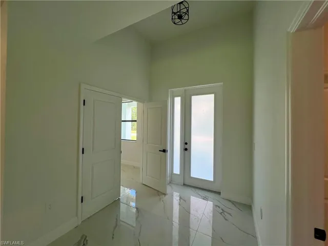 Soaring high ceiling in entry foyer with French doors to the den