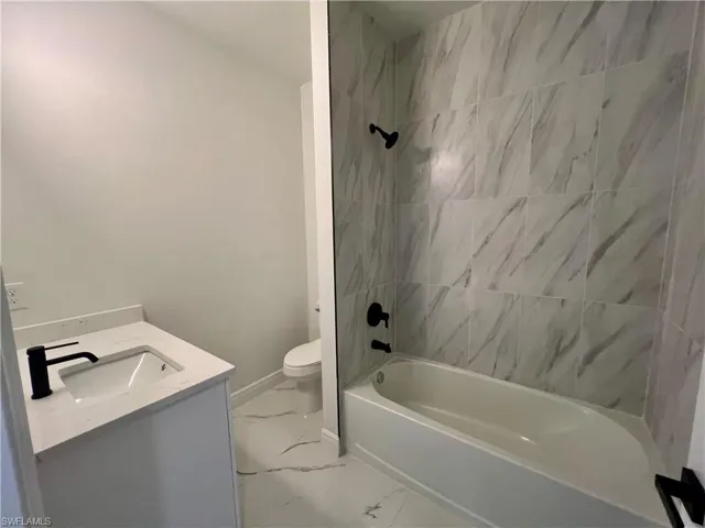 Full bathroom featuring toilet, tiled shower / bath combo, and vanity