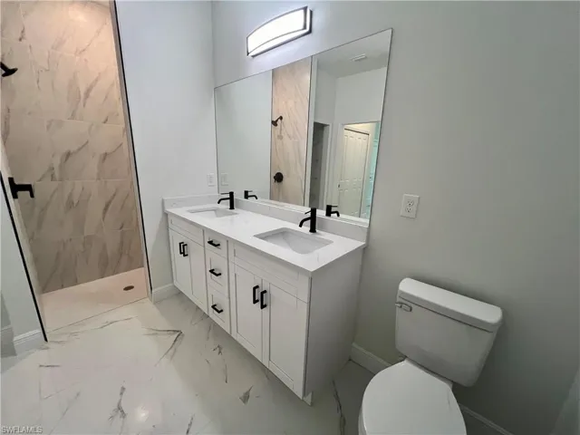 Bathroom with toilet, vanity, and a tile shower