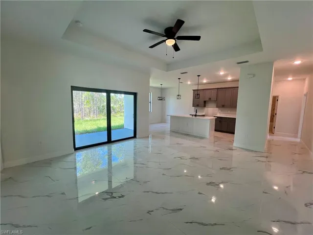 Living room featuring ceiling fan, sink, and a tray ceiling.