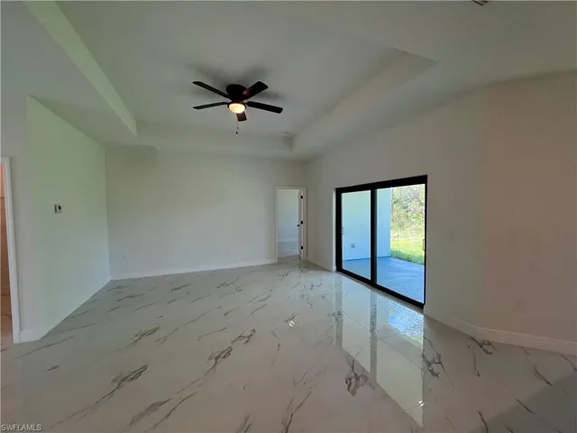 Living room featuring ceiling fan, sink, and a tray ceiling.