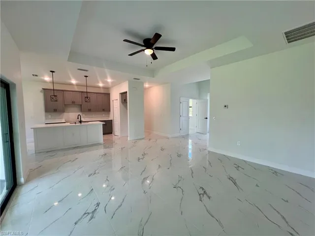 Living room featuring ceiling fan, sink, and a tray ceiling.