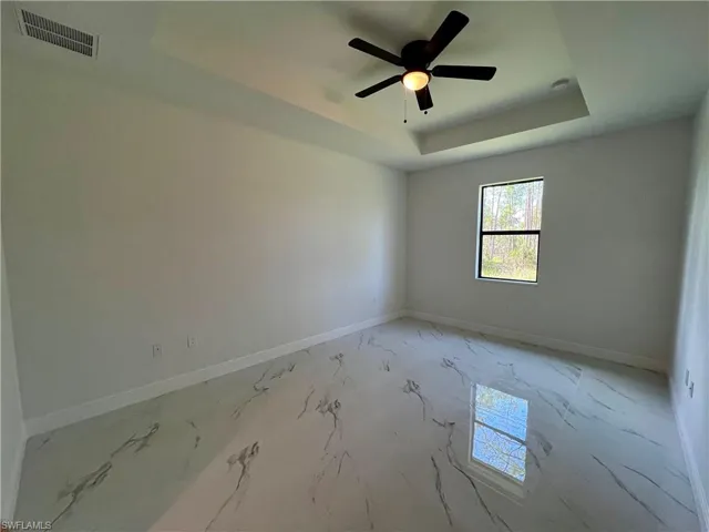 Primary bedroom with ceiling fan and a raised tray ceiling
