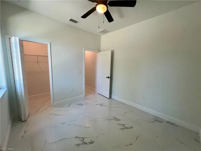Guest bedroom featuring a spacious walk in closet, ceiling fan.