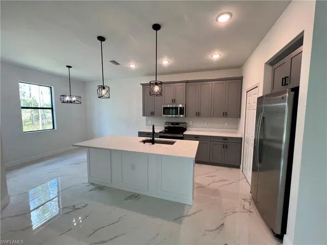 Kitchen featuring stainless steel appliances, hanging light fixtures, a center island QUARTZ TOPS.