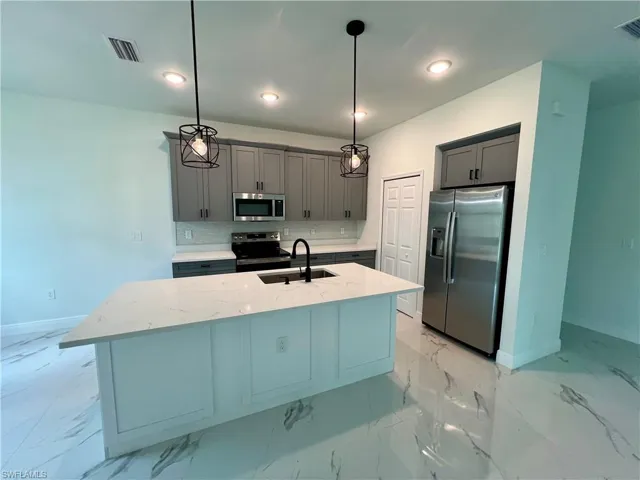 Kitchen featuring stainless steel appliances, sink, decorative light fixtures, and light QUARTZ countertops