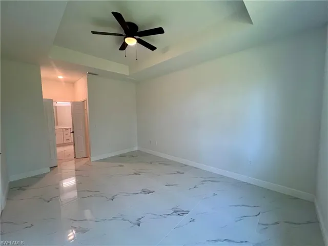 Primary bedroom featuring a tray ceiling and ceiling fan