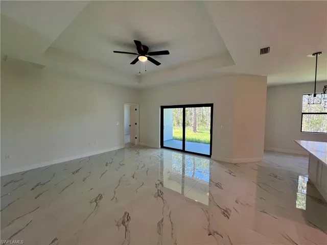 Living room featuring ceiling fan, sink, and a tray ceiling.