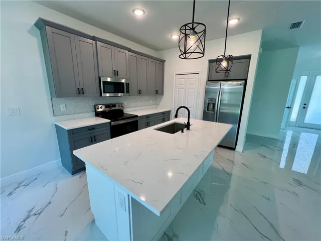 Kitchen with hanging light fixtures, sink, QUARTZ tops and  steel appliances