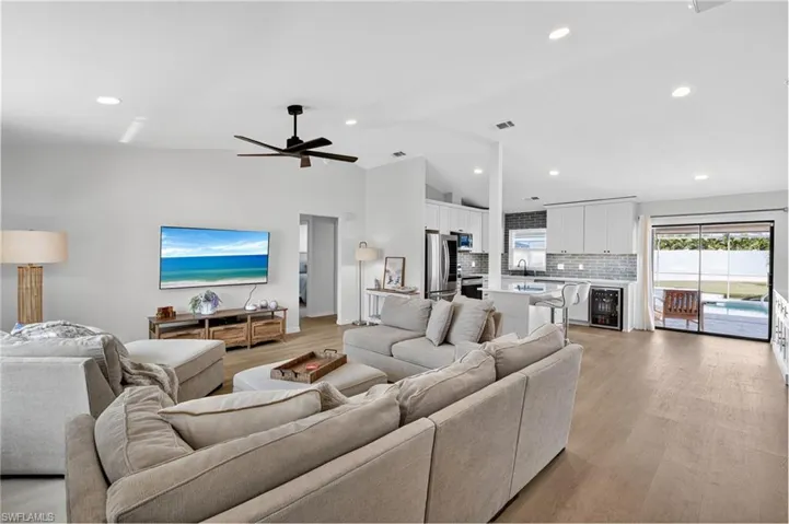 Living area featuring lofted ceiling, wine cooler, light wood finished floors, recessed lighting, and ceiling fan