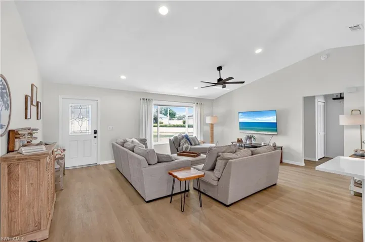 Living area featuring lofted ceiling, recessed lighting, light wood finished floors, and a ceiling fan