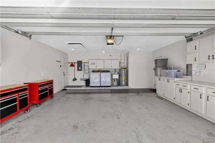 Garage with washer and clothes dryer, electric water heater, electric panel, and a garage door opener