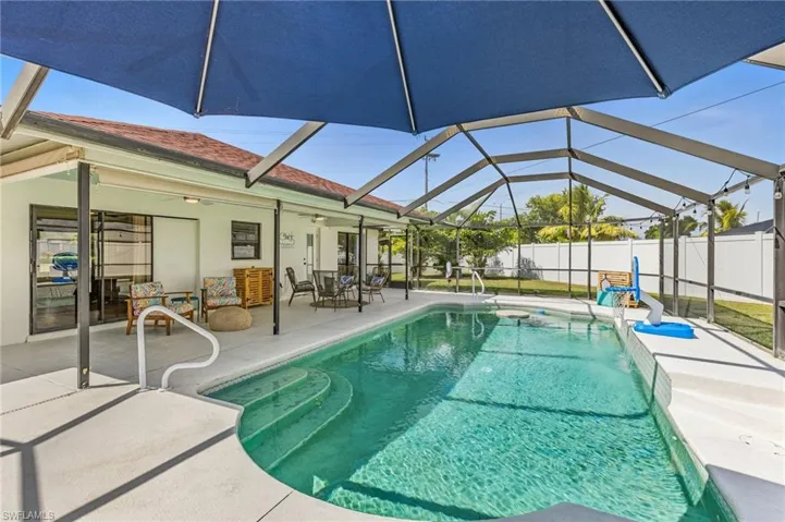 View of swimming pool with glass enclosure, a sunroom, a patio area, and ceiling fan