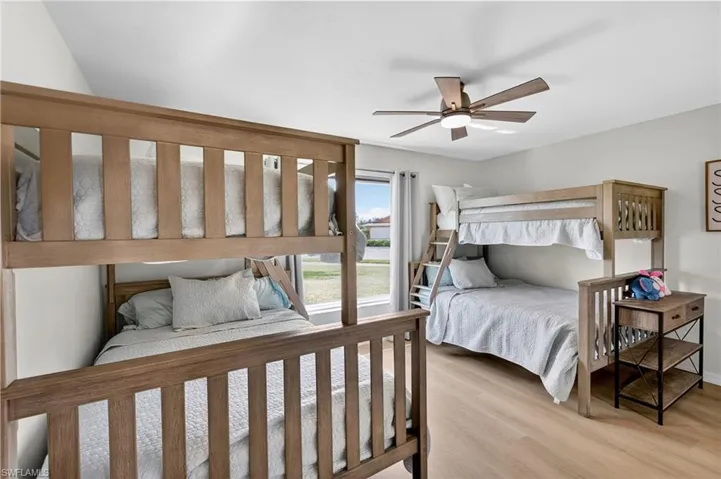 Bedroom with light wood-style flooring, a ceiling fan, and access to exterior