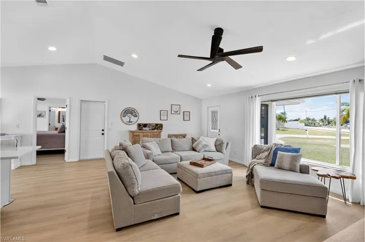 Living room with vaulted ceiling, light wood-style floors, recessed lighting, and a ceiling fan