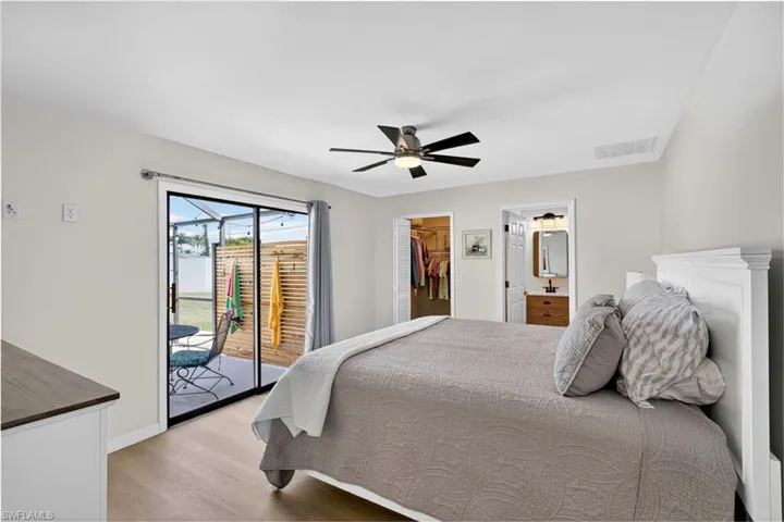 Bedroom featuring light wood-style floors, a walk in closet, access to outside, ceiling fan, and ensuite bath