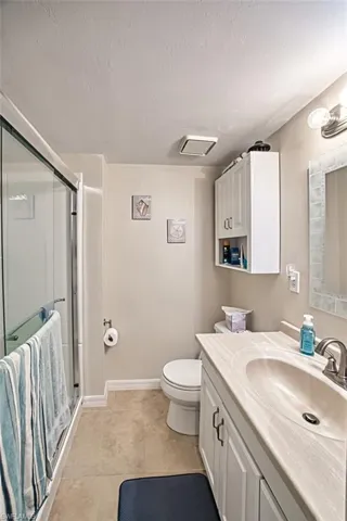 Bathroom featuring tile patterned floors, toilet, vanity, and walk in shower