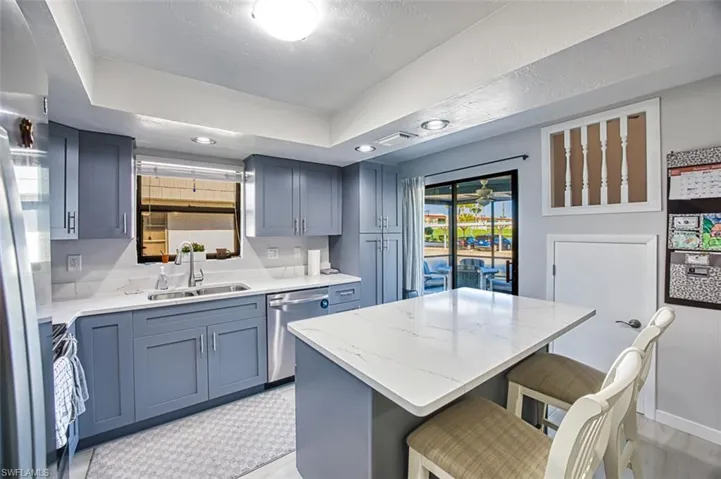 Kitchen with a breakfast bar, a center island, sink, appliances with stainless steel finishes, and a tray ceiling