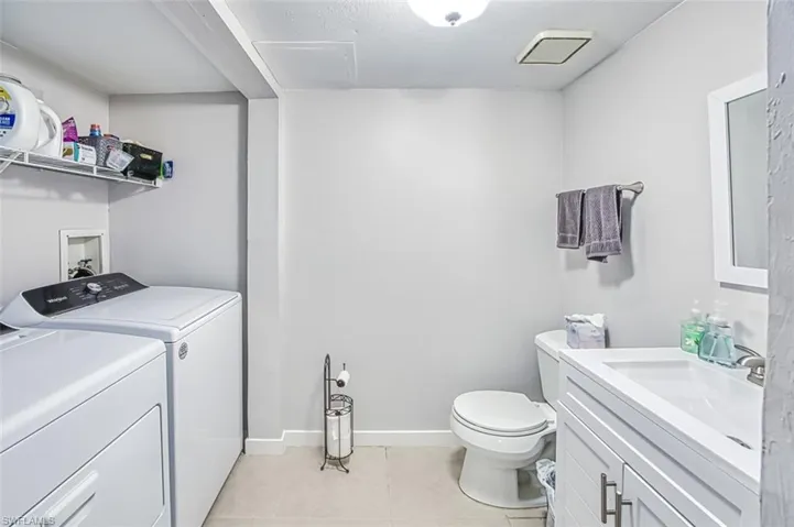 Bathroom featuring tile patterned flooring, vanity, separate washer and dryer, and toilet