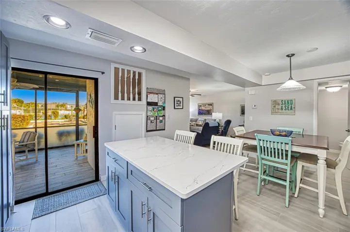 Kitchen with light stone countertops, decorative light fixtures, and a kitchen island
