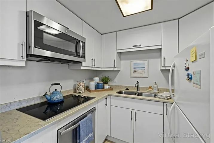 Kitchen with appliances with stainless steel finishes, white cabinets, and light stone countertops