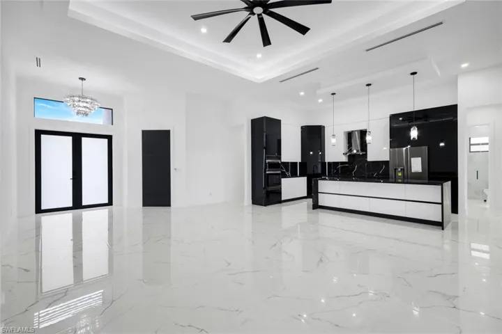 Kitchen with modern cabinets, hanging light fixtures, healthy amount of natural light, a towering ceiling, and dark countertops