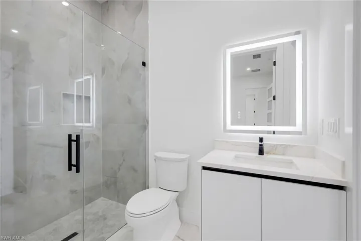 Full bath with vanity, a marble finish shower, and marble look tiles