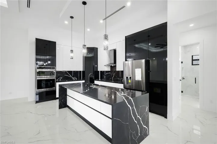 Kitchen with modern cabinets, pendant lighting, dark stone counters, light marble finish flooring, and recessed lighting