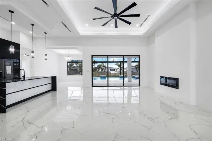 Unfurnished living room featuring light marble finish flooring, a chandelier, recessed lighting, a high ceiling, and a ceiling fan