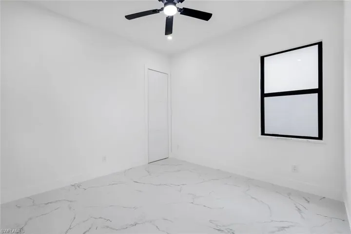 Unfurnished room featuring a ceiling fan and light marble finish flooring
