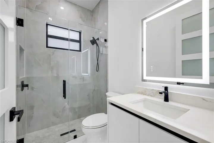 Bathroom featuring a marble finish shower and vanity