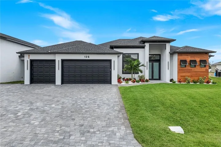 Prairie-style home featuring a front yard, a garage, decorative driveway, stucco siding, and a shingled roof
