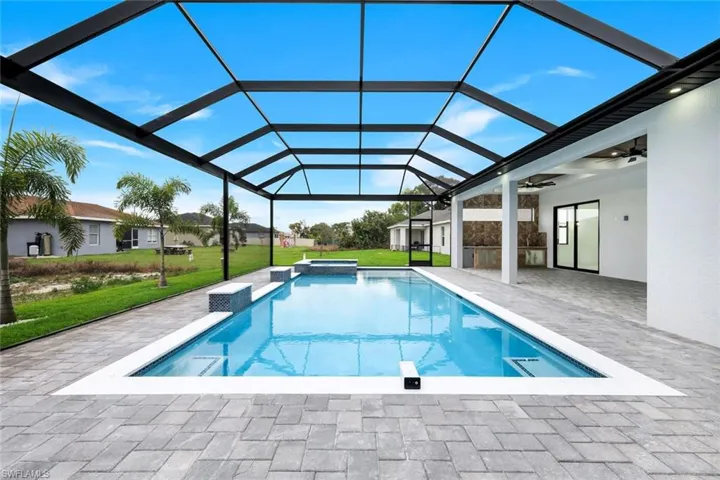 View of swimming pool featuring a sunroom, a yard, a patio area, a pool with connected hot tub, and glass enclosure