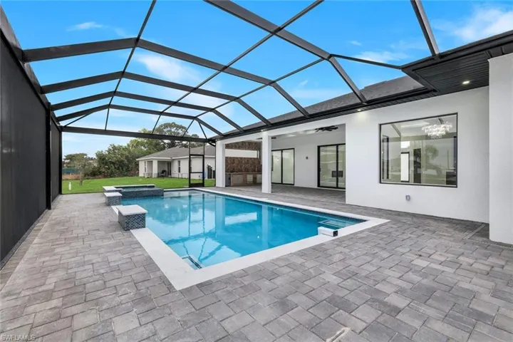 View of pool with a sunroom, a patio area, a pool with connected hot tub, and glass enclosure