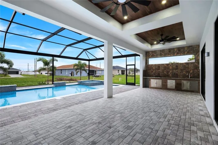 View of swimming pool featuring exterior kitchen, a sunroom, a yard, and a patio