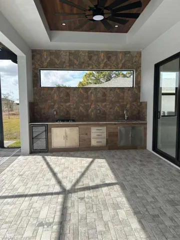 View of patio with exterior kitchen, ceiling fan, and beverage cooler
