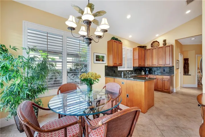 Kitchen featuring high ceiling, tasteful backsplash, sink, kitchen peninsula, and an inviting chandelier.