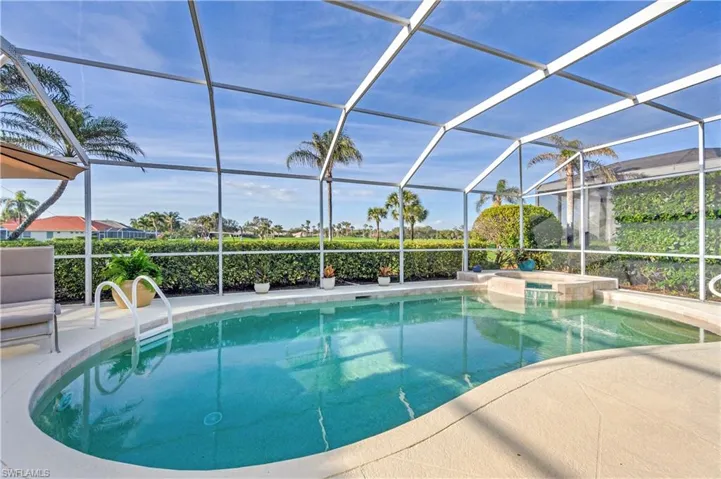 View of pool with a waterfall spa and screened lanai.