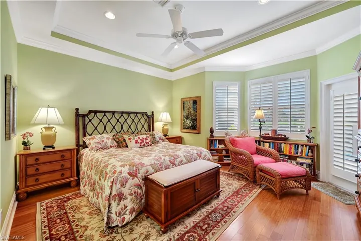 Main Bedroom with crown molding, ceiling fan, and bamboo flooring. PLantation shutter and door to the Lanai and Pool.
