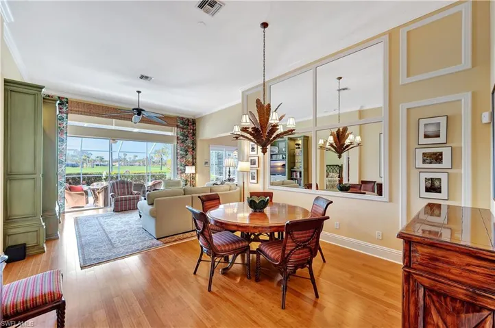Dining area with ornamental molding, ceiling fan with notable chandelier, and bamboo flooring