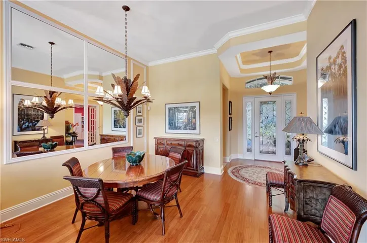 Dining area featuring ornamental molding, a tray ceiling, hardwood / wood-style floors, and a notable chandelier