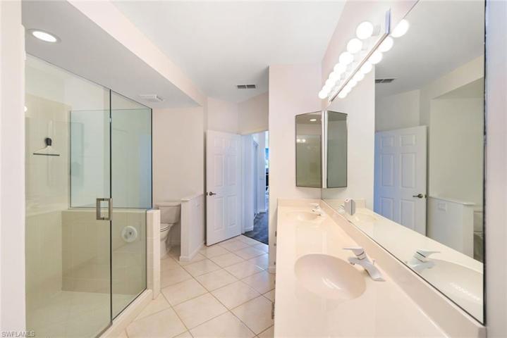 Great primary bathroom with double sinks and frameless glass walk-in shower with modern square shower door handle.