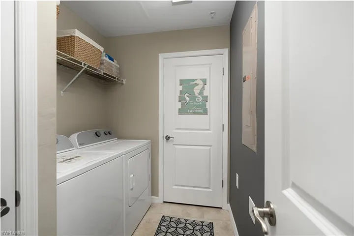 Laundry room with washer and clothes dryer and light tile patterned flooring