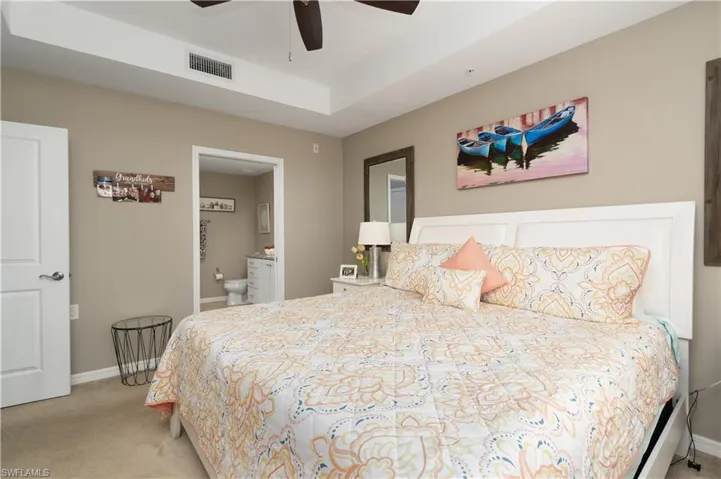 Bedroom with carpet floors, ensuite bath, and a ceiling fan