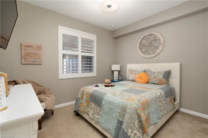 Bedroom featuring light carpet and baseboards