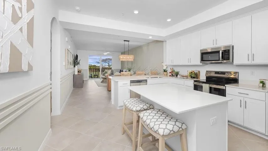 Kitchen with stainless steel appliances, white cabinetry, pendant lighting, a kitchen bar, and a peninsula