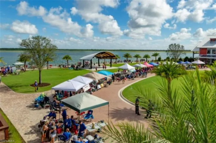 View of community with a lawn, a water view, and a patio
